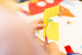 Schülerin schneidet mit einer Schere eine selbstgemalte Giraffe aus