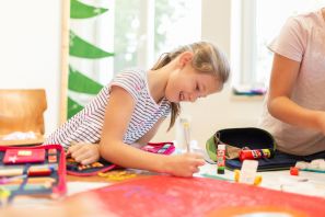 Schülerin lehnt an einem Tisch und malt ein Bild