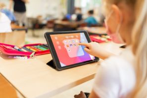 Schülerin arbeitet im Unterricht mit einem Tablet und tippt mit ihrem Finger eine App an